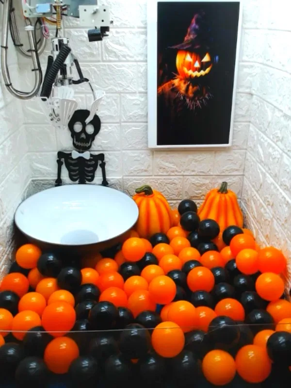 Inside the Halloween claw machine: Pumpkin Snatcher on the display above a pit of orange and black balls