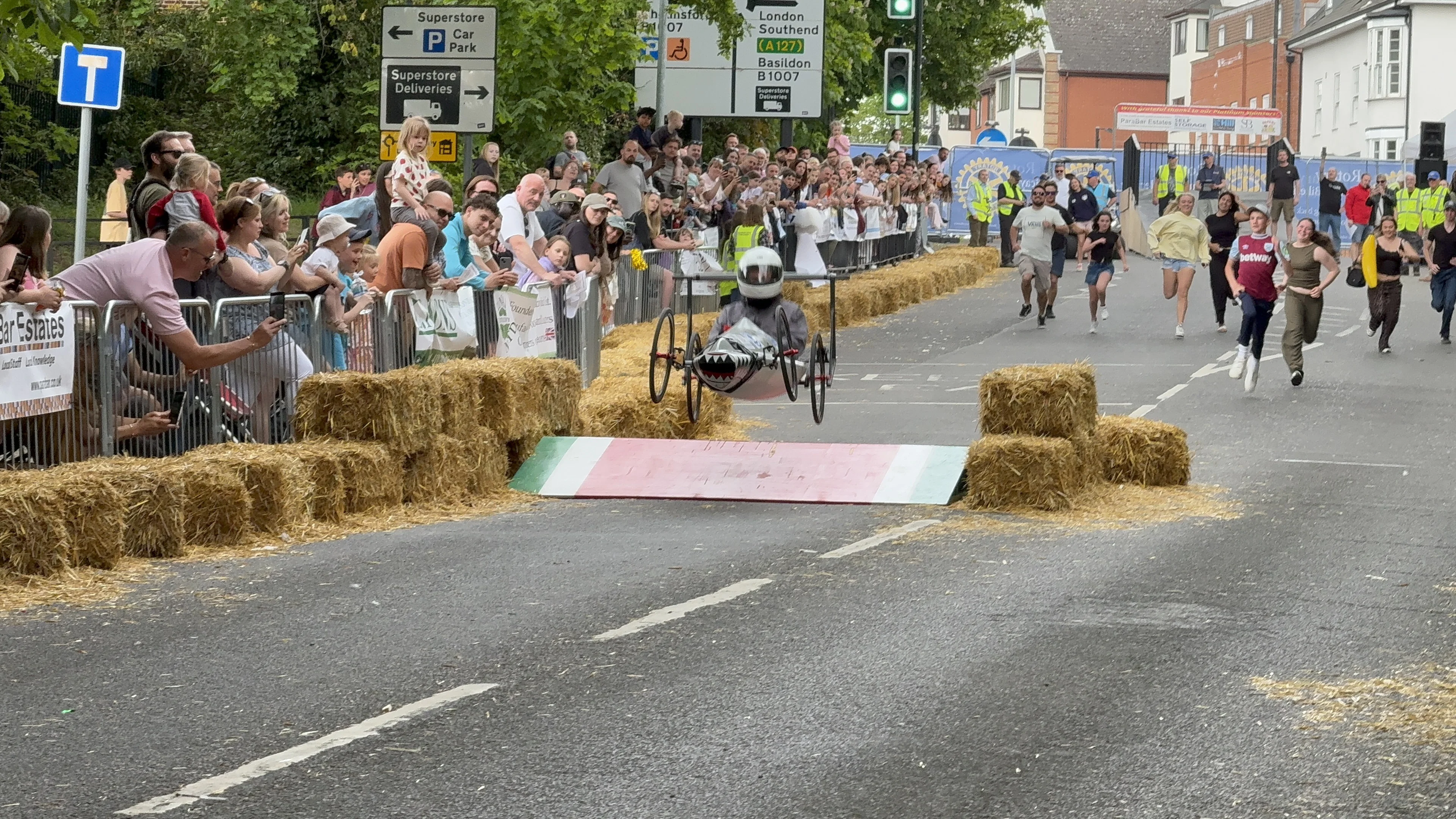 Shark Attack soapbox cart catching air over a ramp at the Billericay Soapbox Race 2026, in front of packed crowds.